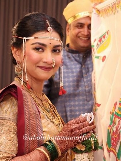 A sweet moment during the wedding ceremony. The bride's natural-looking makeup, complete with a traditional nath and mundavalya, enhances her gentle smile.