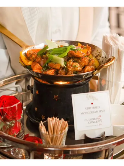 A server presents a tray of Stir Fried Mongolian Fish in a miniature chafing dish. This allows us to serve hot appetizers that stay warm as they are passed among guests, ensuring the perfect temperature with every bite.