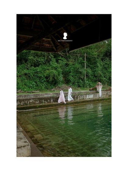 Another perspective from the temple pond shoot, capturing the couple's reflection as they walk by the water's edge.