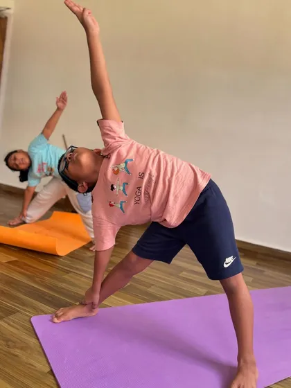 A young student practices Trikonasana, or triangle pose. This foundational pose is excellent for stretching the entire body and building strength in the legs.