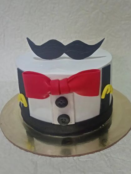 A classic gentleman-themed cake, featuring a tuxedo shirt, red bow tie, and a mustache topper. Simple, elegant, and perfect for any man's celebration.
