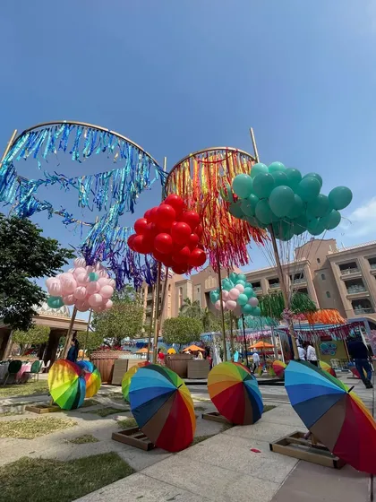 Whimsical decor elements from the carnival, including colorful balloon clouds, rainbow umbrellas, and streamers, designed to create a playful and visually exciting environment.