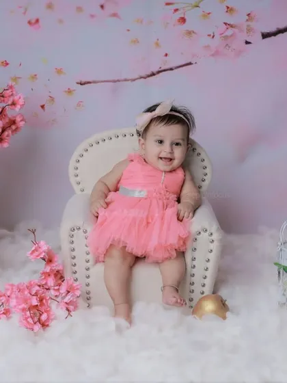 This baby girl in a pink dress is surrounded by cherry blossoms. The soft, dreamy set is perfect for a beautiful and feminine sitter session.