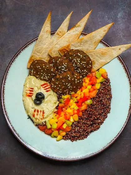 A deconstructed falafel platter with hummus, quinoa, fresh salsa, and crispy pita points arranged artfully. The moody lighting and overhead perspective make this a perfect shot for a modern Mediterranean restaurant.