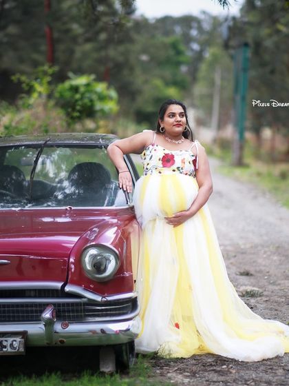 A unique outdoor portrait with our yellow and white floral gown, posed against a vintage car for a retro-chic vibe.