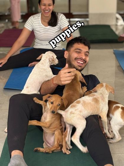 A participant laughs as he sits on his mat, completely surrounded by a group of energetic and adorable puppies.