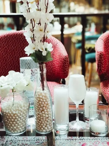 A close-up of the white-themed table decor, showing the mix of textures with pearls, glass, and flowers.
