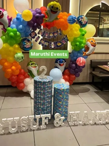 A joint birthday party with a rainbow Baby Shark theme. The circular balloon arch and light-up names make it a special celebration for two.