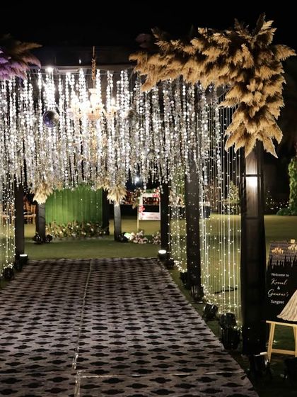 The entrance to the sangeet, where pampas grass in purple and natural tones adds a touch of boho glam to the sparkling decor.