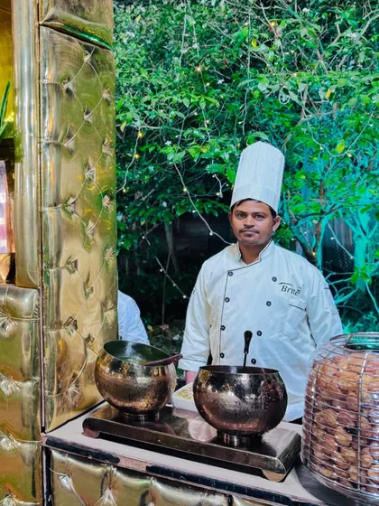 My chef stands ready at the chaat station, which is elegantly decorated with golden bowls and lush greenery.