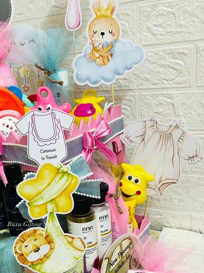 A detailed shot of the baby shower hamper, showing the cute bunny and bear cutouts and the variety of toys and essentials packed inside.