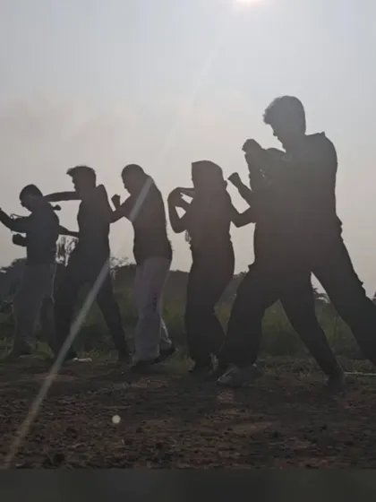A silhouette of students practicing their stances during an early morning outdoor session.