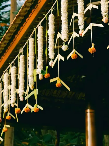 A detail from our Muhurtham series, focusing on the simple beauty of jasmine and marigold strings hanging from a traditional tiled roof.