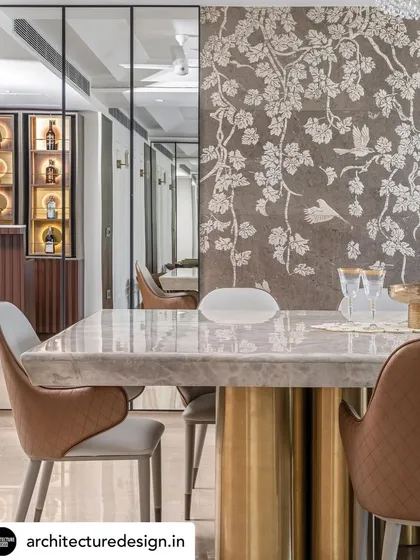 The dining area features a magnificent marble tabletop with a sculptural brass base. A custom stone mosaic wall provides an artistic backdrop, while mirrored panels expand the sense of space and reflect the room's opulent details.