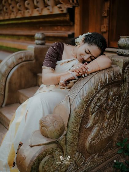A peaceful, artistic portrait of the bride resting on an ornate stone bench, a moment of quiet contemplation.