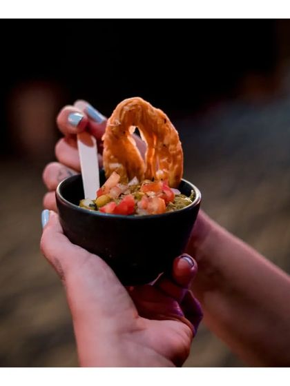 A guest holds a small bowl of our Ghugni Chaat, topped with a crispy papdi. This modern presentation of a rustic street food classic makes it perfect for an upscale event.