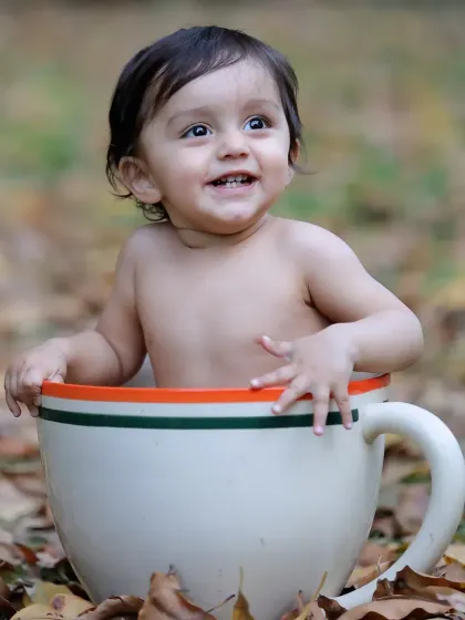 A happy baby enjoying an autumn day in our teacup prop. The fallen leaves on the ground create a beautiful, seasonal atmosphere.