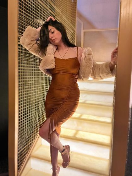 A softer, more candid pose in the brown dress, showing a different side of the same outfit.