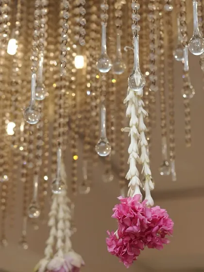 A detail shot of a crystal chandelier with hanging strings of fresh flowers. This shows how I blend modern decorative elements with traditional touches to create a unique and elegant look for religious events.