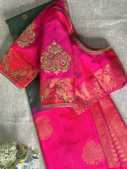 The full view of the pink Kanjeevaram blouse laid over its matching green saree, showcasing the beautiful color contrast and sleeve design.