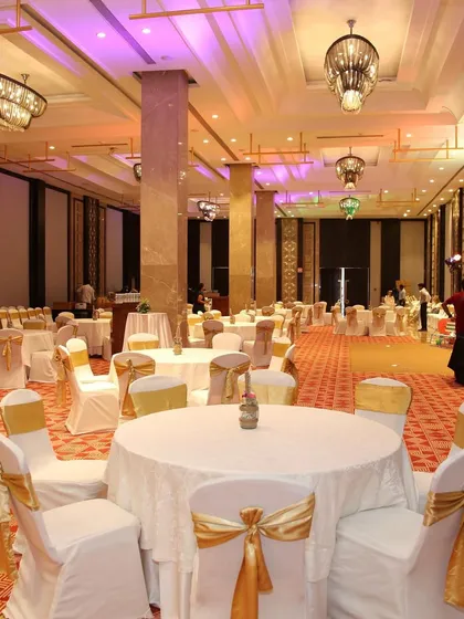 A classic banquet hall setup with gold and white decor, ready for a large reception or corporate event.