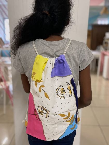 A student shows off her hand-painted backpack, a unique accessory she designed and created in our workshop.