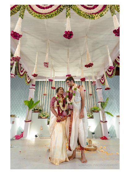 A full view of the mandap during a South Indian wedding, showing the couple standing together under a canopy of flowers.