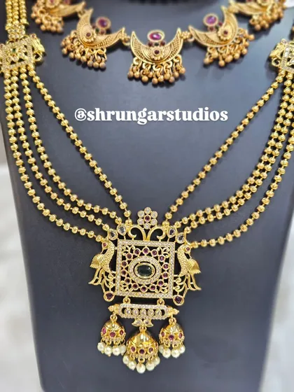 The long, multi-strand chain with a statement peacock pendant adds a grand touch to this ensemble.