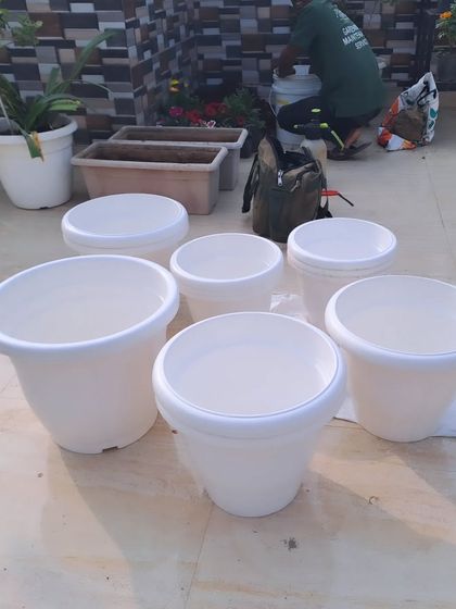 Getting ready for a planting project. A collection of clean, white plastic pots of various sizes are prepared before being filled with soil and new plants.