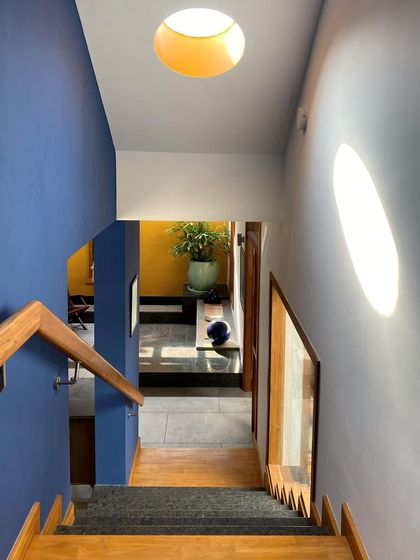 Color and light work together in this stairwell. A deep blue wall contrasts with the bright light from a circular skylight, creating a visually interesting journey between floors.