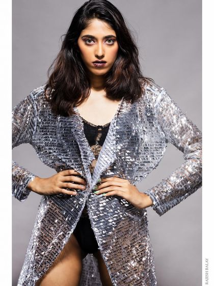 A model in a silver sequin jacket, with a powerful and direct pose.