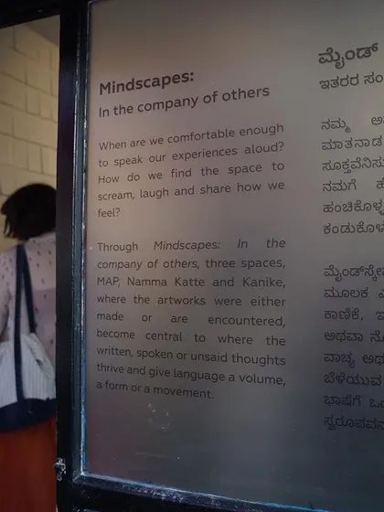A visitor reads the curatorial note for the "Mindscapes" exhibition, which was presented in both English and Kannada to be accessible to our local community.
