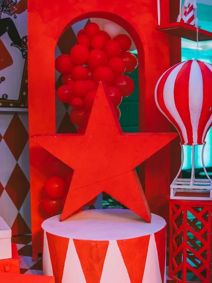 A collection of bold, red props, including a star and a hot air balloon, add to the vibrant circus atmosphere. I use strong shapes and colors to create a dynamic and exciting visual landscape.
