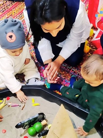 An instructor guides two of our youngest learners in a sand play activity. These moments of shared discovery are central to our parent-child programs.
