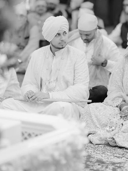 The couple seated during their Anand Karaj ceremony. This candid shot captures a quiet moment of reflection and togetherness in a sacred space.