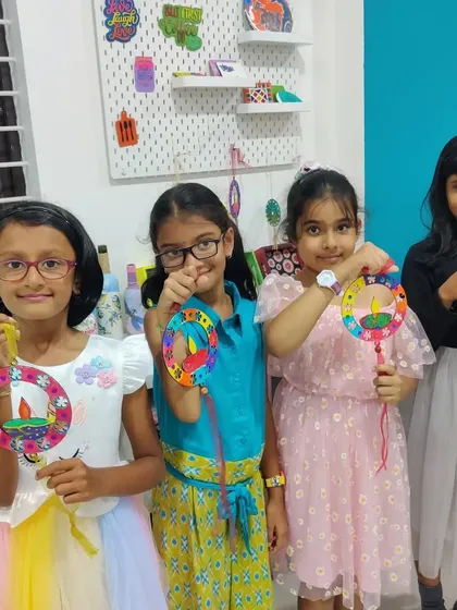 Four girls displaying the lovely Diwali wall hangings they made. Each one is unique and colorful.