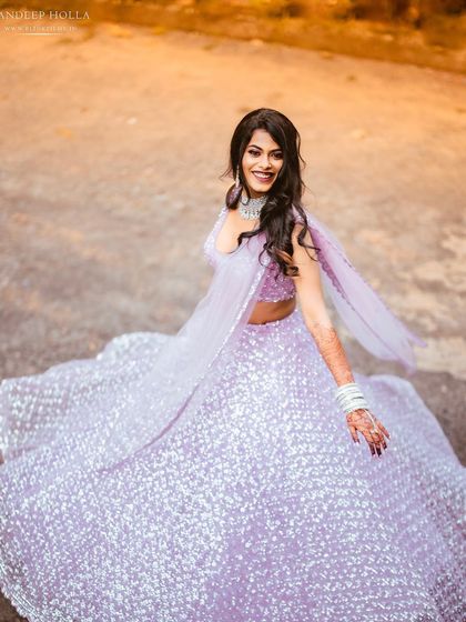 A vibrant, happy portrait of a bride twirling in her beautiful lavender lehenga.