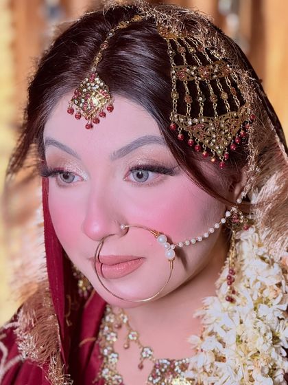 A detailed close-up of the bride's makeup. The look features a flawless base, rosy cheeks, and a soft nude lip.