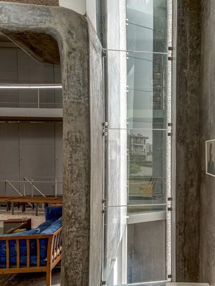 A detail of the cast-in-situ concrete and glass elevator shaft within the Artrovert studio, showcasing the project's honest and expressive use of materials.