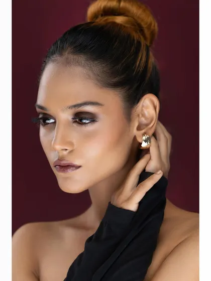 An elegant beauty portrait with a model in a high bun, showcasing dramatic smokey eye makeup and a sophisticated pose.