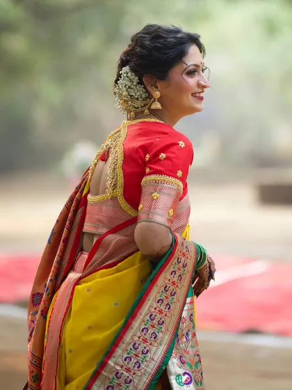 A side profile showing the intricate hairstyle, a classic bun adorned with fresh gajra, which perfectly complements the traditional yellow Nauvari saree.
