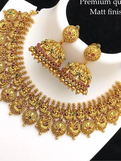 A matte-finish temple necklace with matching jhumkas. The intricate carvings and classic design make it a favorite for South Indian ceremonies.