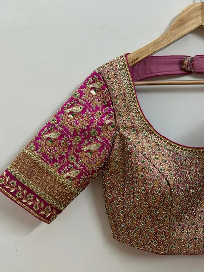 Another angle of the peacock motif blouse, showing the detailed craftsmanship and the shimmer of the zardosi work against the rich pink silk fabric.