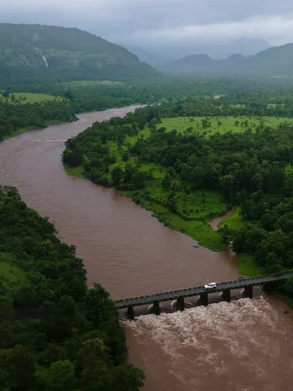 A car crossing a bridge over a swollen river in Mahad, Konkan. This shot captures the adventurous spirit of a monsoon road trip in the region.