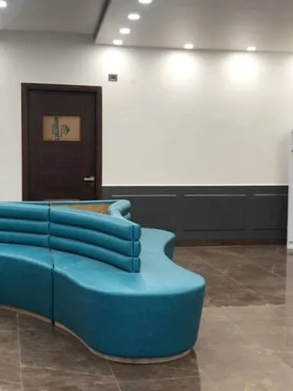 A wider view of the school's reception lounge, showing how the custom sofa anchors the large, open space. The layout is designed to be spacious and easy to navigate.