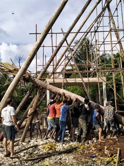 Teamwork in action as a large timber pole is maneuvered into place for the spa's framework. Building these structures requires significant manpower and coordination.