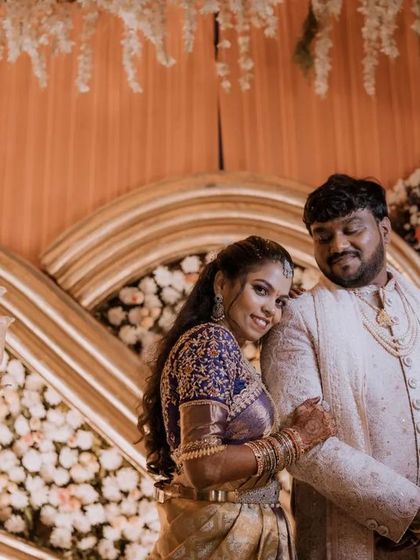 A candid moment of the bride leaning affectionately on the groom's shoulder during their reception. The grand floral decor adds to the romantic ambiance.