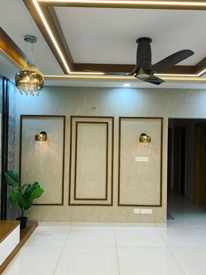 This living room wall features a beautiful design using teak wood moulding. The simple frames create a sophisticated and elegant highlighter wall, complemented by classic wall sconces.