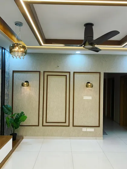 This living room wall features a beautiful design using teak wood moulding. The simple frames create a sophisticated and elegant highlighter wall, complemented by classic wall sconces.