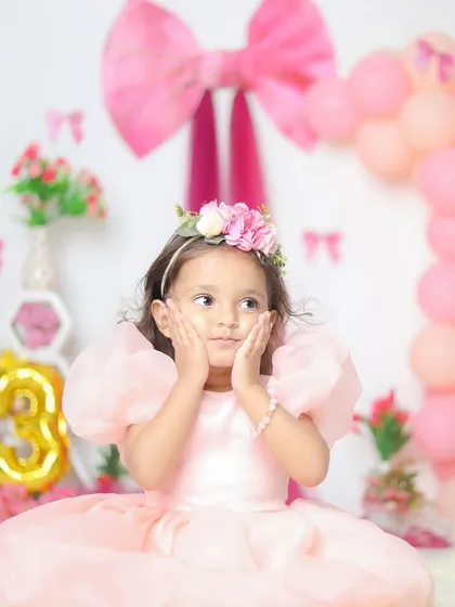 The many adorable faces of a three-year-old princess. This pink bow and balloon setup is perfect for celebrating her special day.